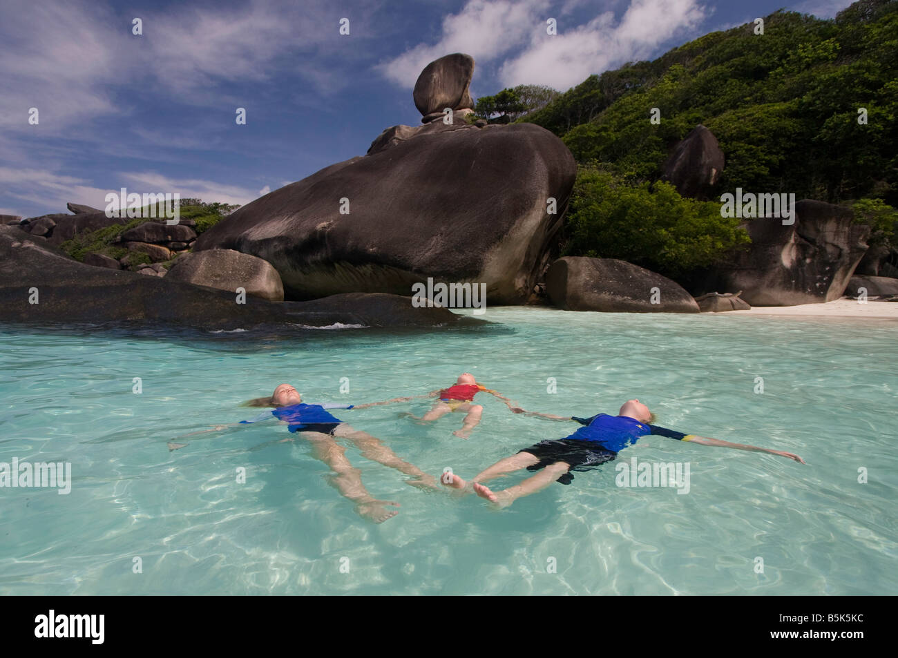 3 enfants flottant dans l'eau bleue et claire dans Donald Duck Bay dans les îles Similan Banque D'Images