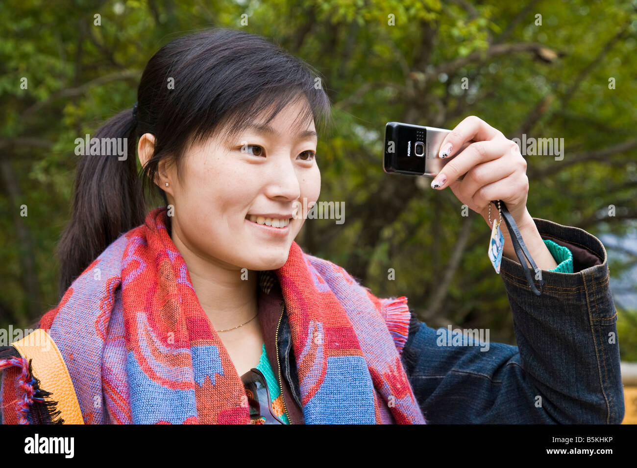 Jeune femme chinoise oriental asiatique avec écharpe aux couleurs vives en  photographie à l'aide d'Nokia cellphone Huanglong Chine JMH3531 Photo Stock  - Alamy