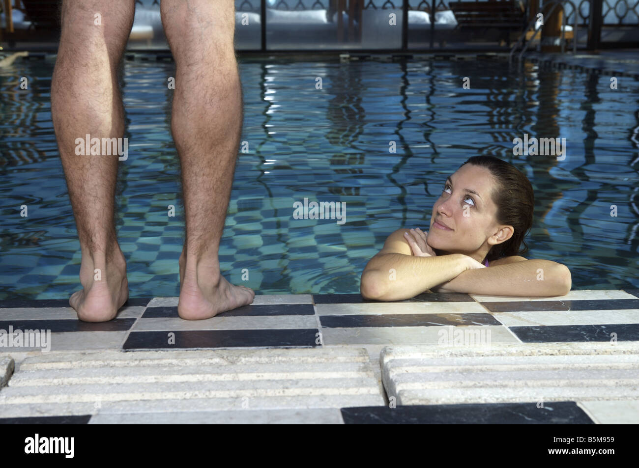 Une femme dans la piscine à la recherche jusqu'à un homme. Banque D'Images
