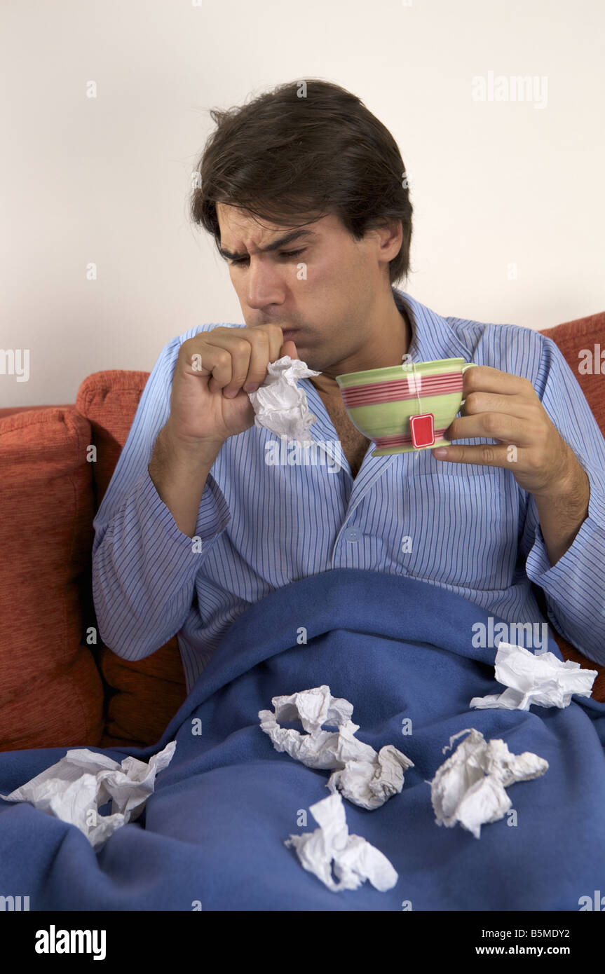 La toux d'un homme tout en tenant une tasse Banque D'Images