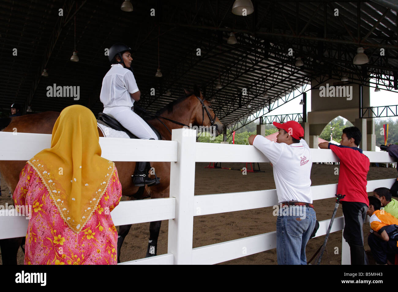 Spectateurs regardant rider le réchauffement de l'cheval avant une compétition de saut à Terengganu, Malaisie. Banque D'Images