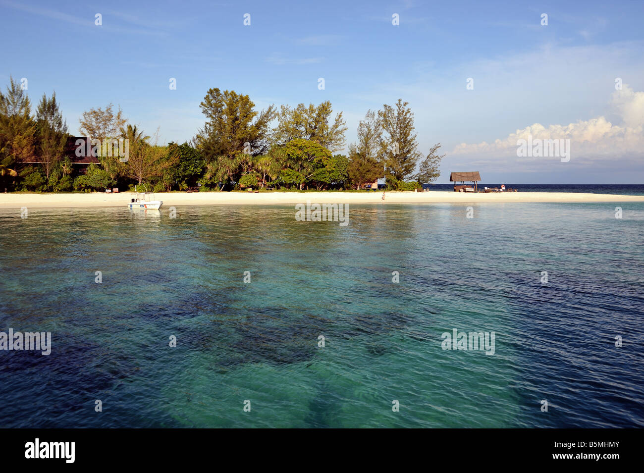 Plage de sable fin sur Lankayan Island montrant l'eau claire, de ciel bleu et de la végétation et un petit bateau amarré. Banque D'Images