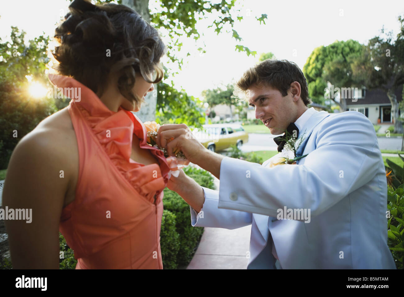 Jeune homme aidant avec corsage de la jeune femme Banque D'Images