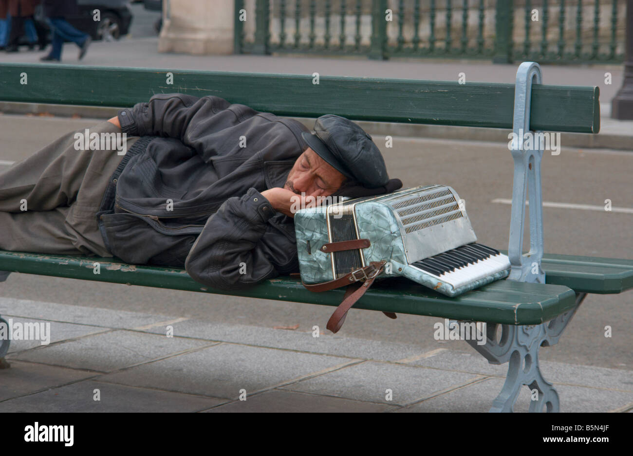 Musicien ambulant de dormir sur un banc, la tête reposée sur son accordéon Paris France Banque D'Images