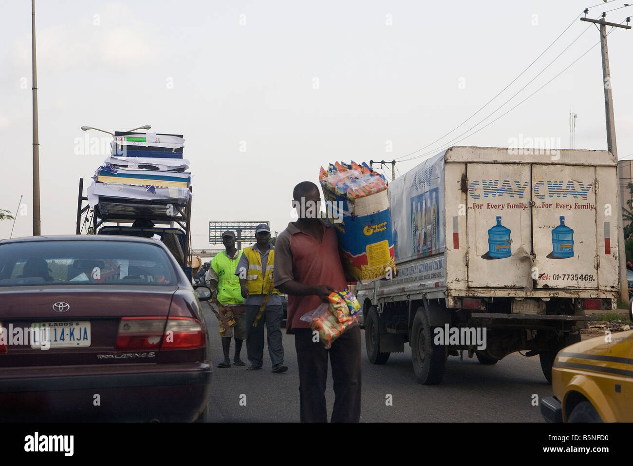 Les vendeurs de rue à pied entre les voitures dans un embouteillage à la sortie de Lagos, au Nigeria, au cours du début de soirée Banque D'Images