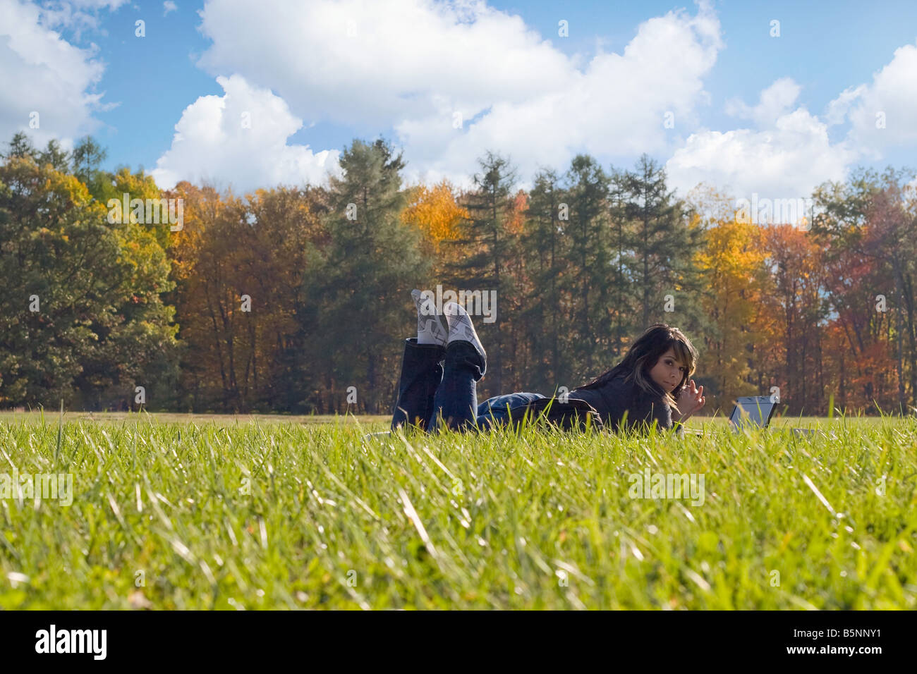 Un jeune étudiant en utilisant son ordinateur portable tout en jetant dans l'herbe par une belle journée Banque D'Images