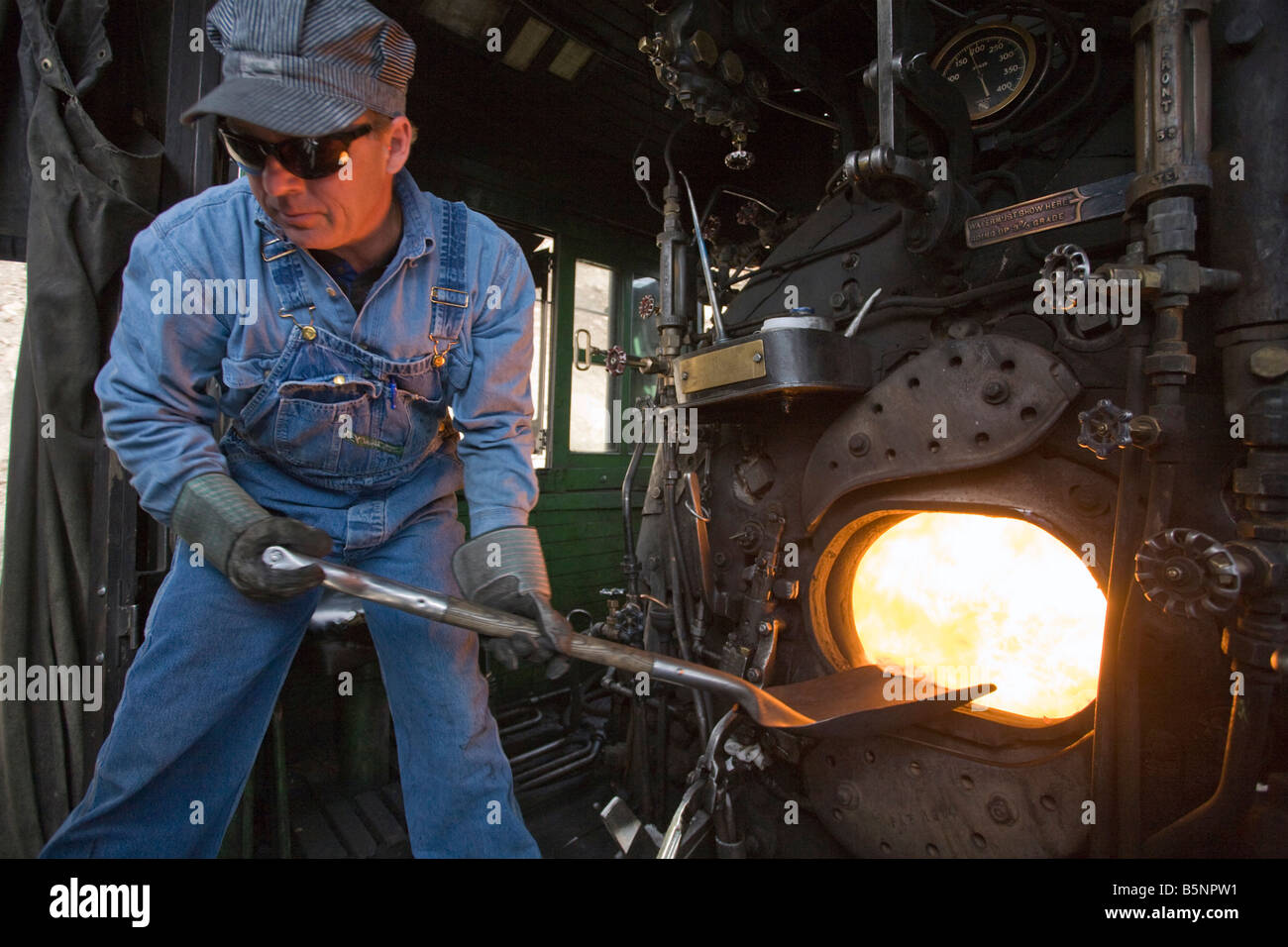 Un pompier de pelles dans le feu de charbon fort d'une locomotive à vapeur sur le Durango Silverton Narrow Gauge Railroad Banque D'Images