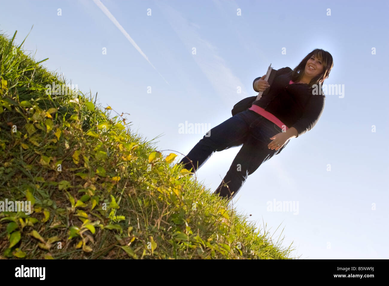 Une jeune étudiante posant sur une colline herbeuse sur le campus de l'école Banque D'Images