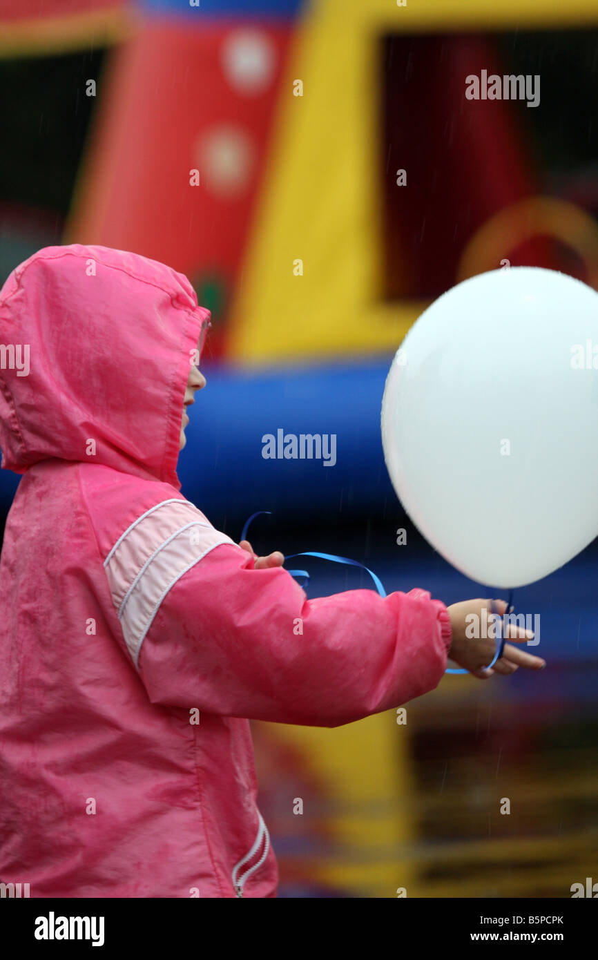 Un enfant jouant avec un ballon à un salon de la sécurité incendie dans la pluie Banque D'Images