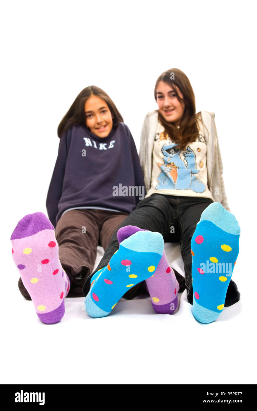 Close up vertical de deux adolescentes pieds aux couleurs de polka dot Winter socks sur sur un fond blanc. Banque D'Images