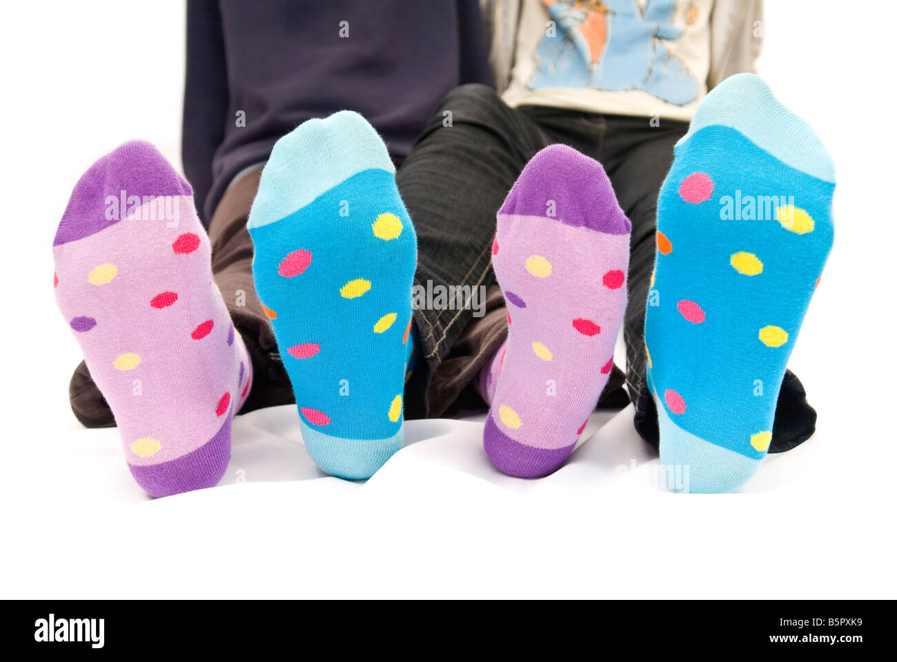 Close up horizontal de deux adolescents pieds pour enfants aux couleurs spotty Winter socks sur sur un fond blanc. Banque D'Images