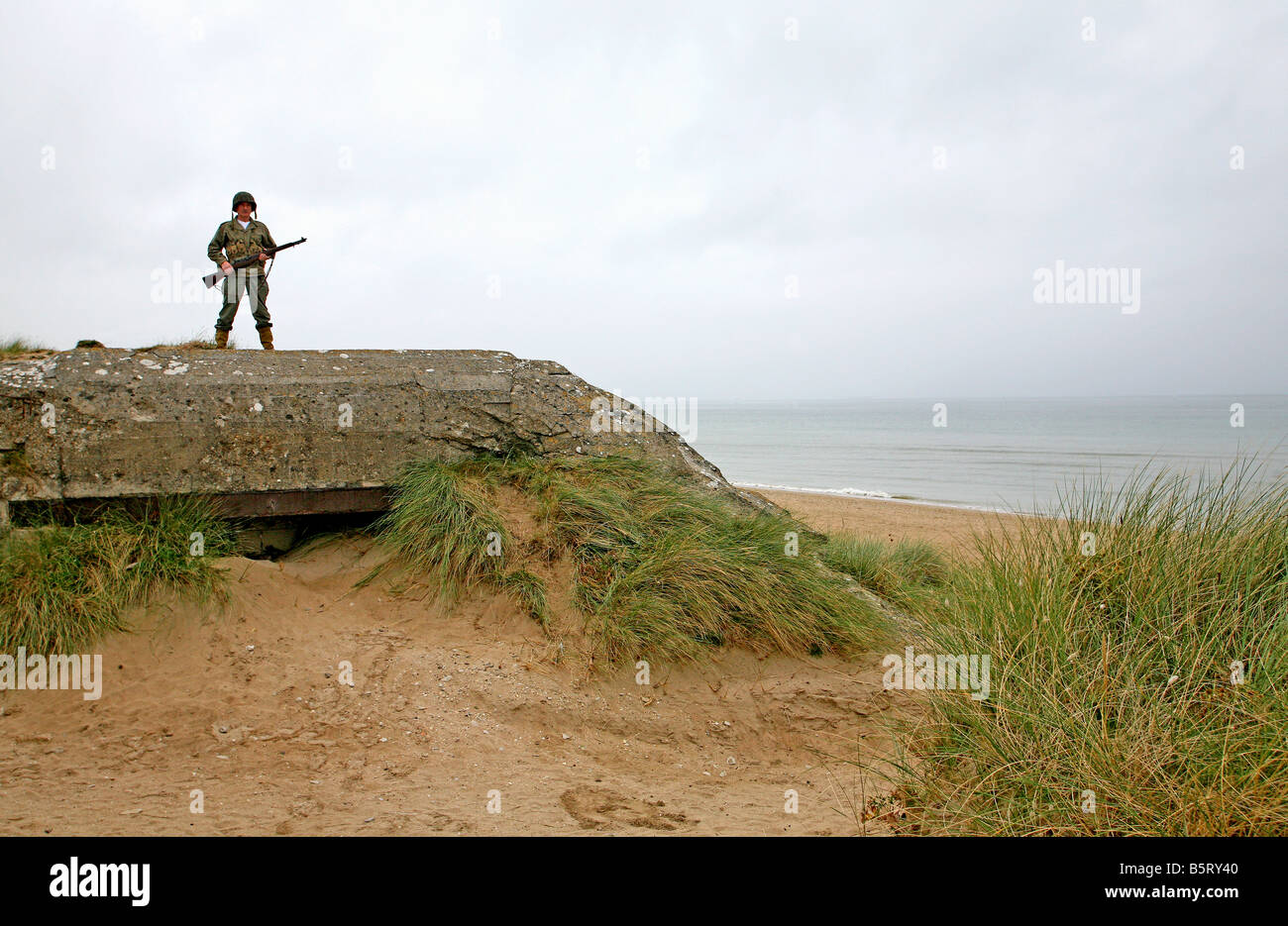 Acteur habillé en D-Day American soldier debout sur un bunker allemand à Utah Beach en Normandie, France Banque D'Images