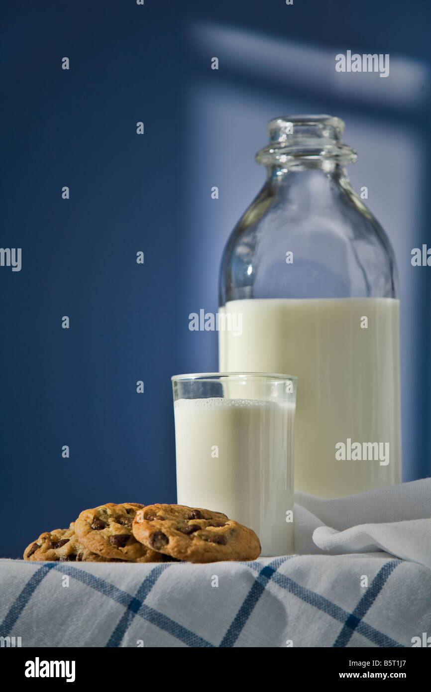 Verre et bouteille de lait avec des cookies sur un fond bleu Banque D'Images