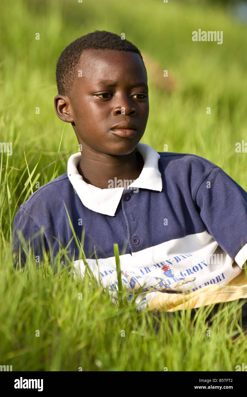 Jeune africain lying in grass regardant le Festival Evala du Togo Banque D'Images