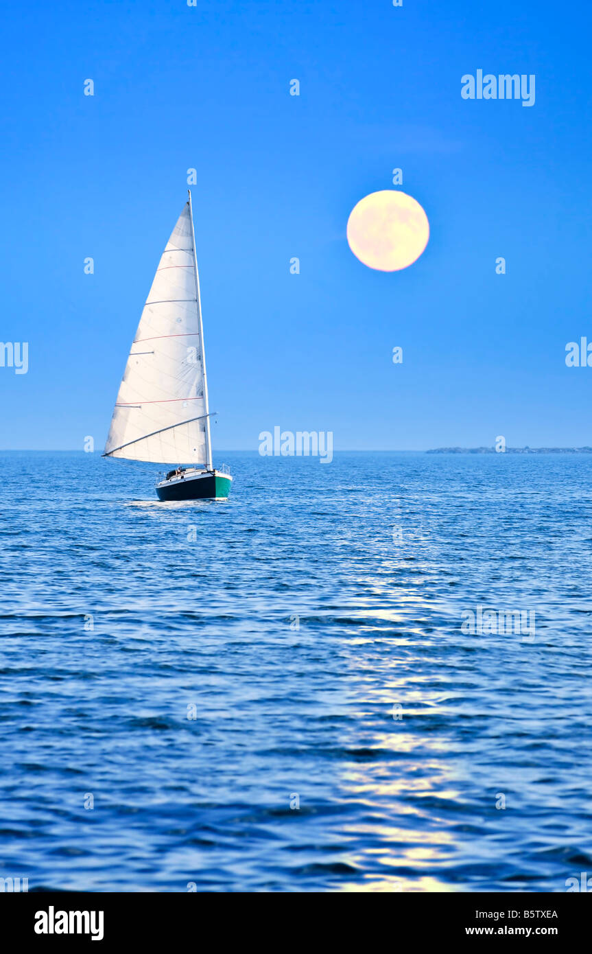 Voilier naviguant dans une mer à la pleine lune nuit Banque D'Images