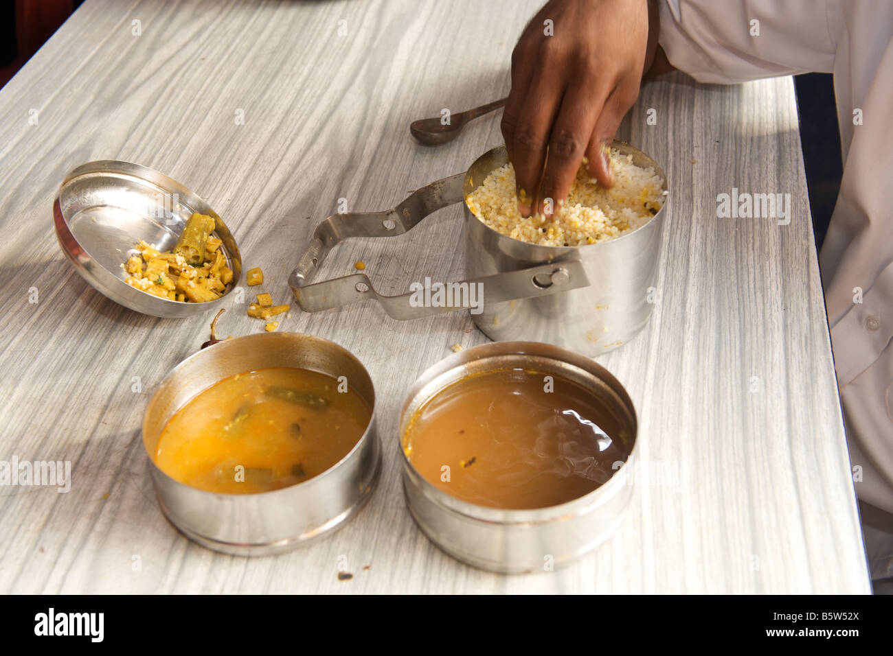 L'homme manger du riz avec des cochons et cari de légumes à partir de ses sandwichs de (boîte à lunch) à Pondichéry, en Inde. Banque D'Images