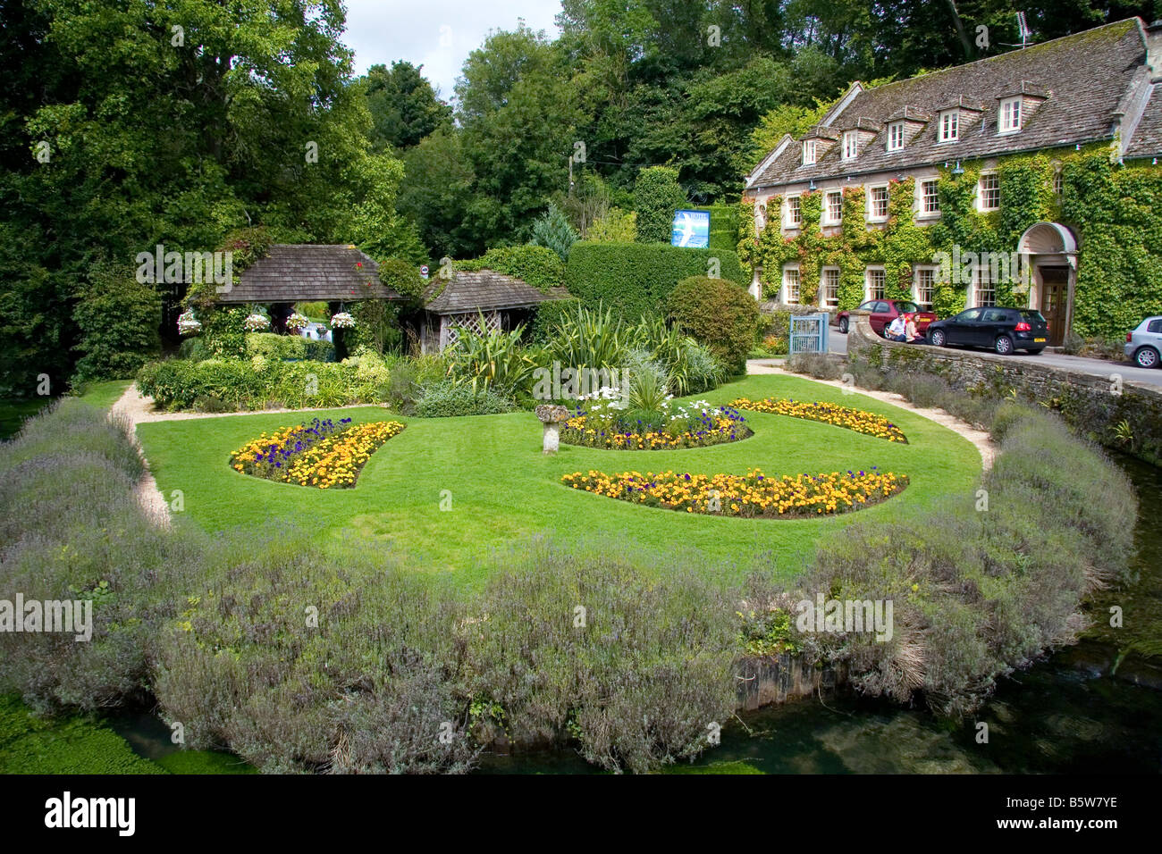 Jardins et fontaine ferme dans le village de Bibury Gloucestershire Angleterre Banque D'Images