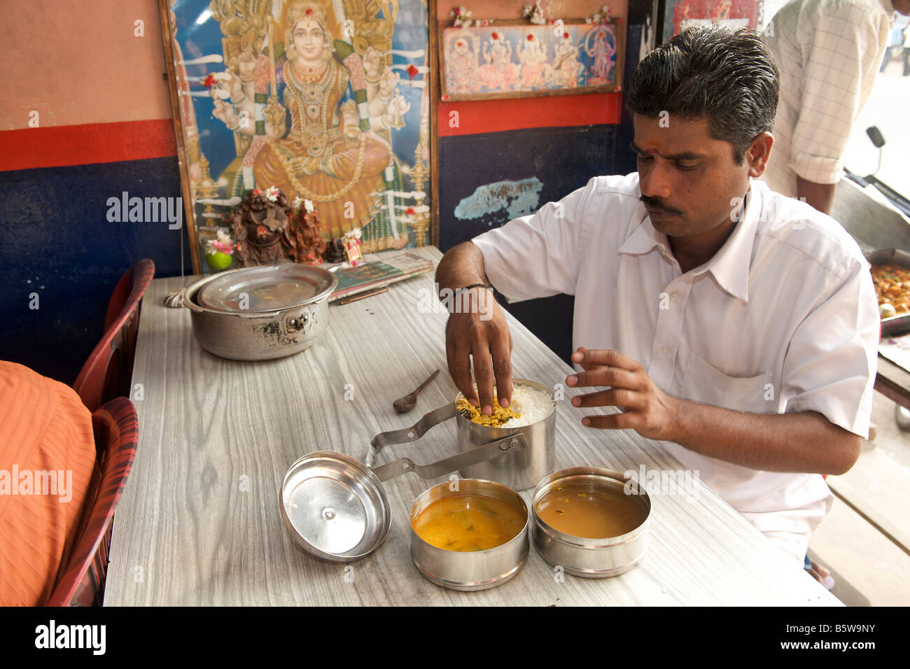 L'homme manger du riz avec des cochons et cari de légumes à partir de ses sandwichs de (boîte à lunch) à Pondichéry, en Inde. Banque D'Images