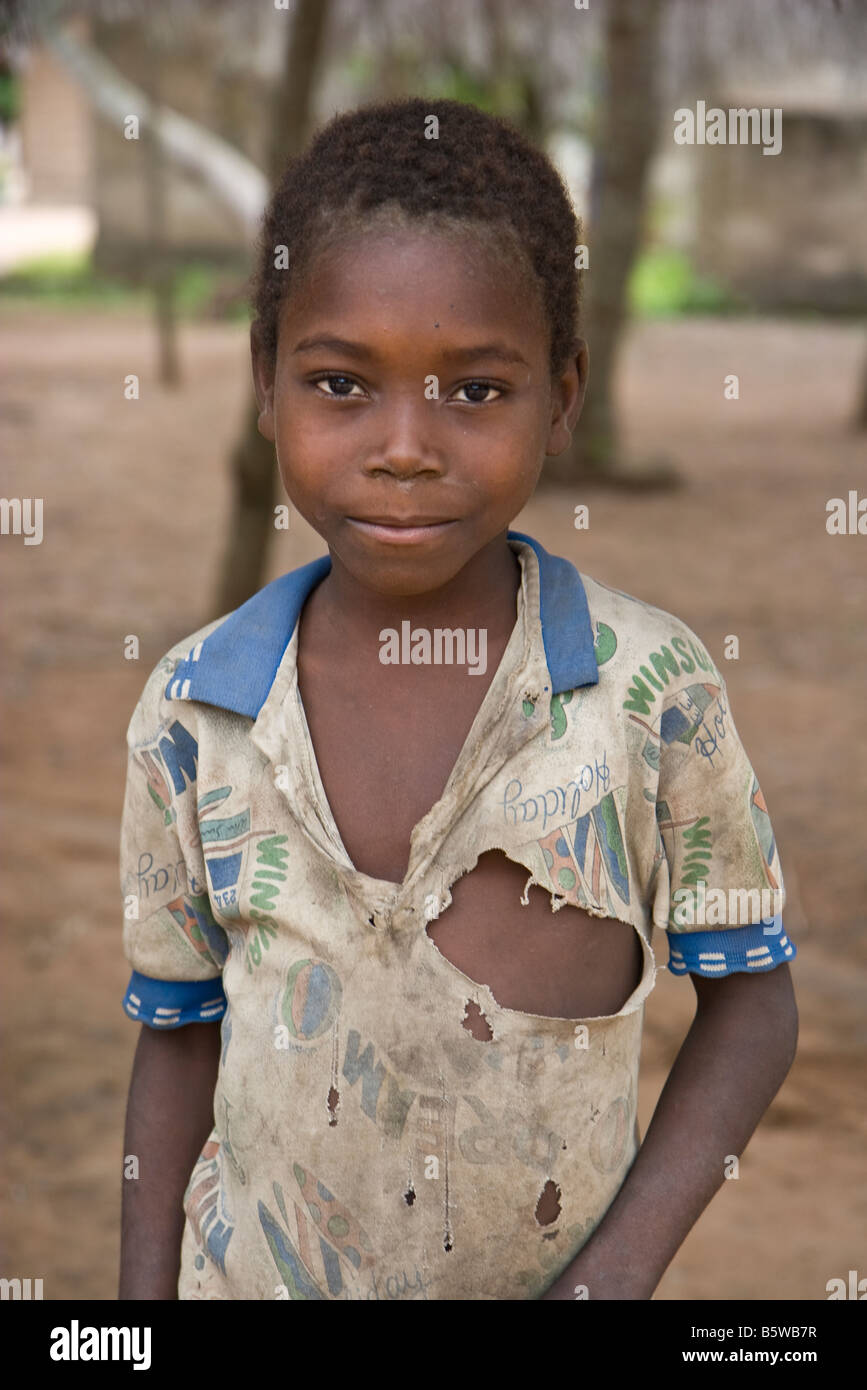 African boy avec sale, t-shirt déchiré en souriant à la caméra. Son village bénéficie d'un projet d'aide humanitaire. Banque D'Images