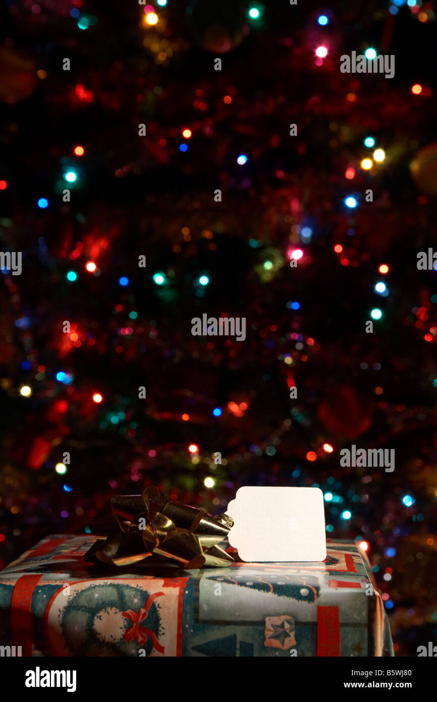 Haut de wrapped christmas présent montrant name tag in front of Christmas Tree Banque D'Images