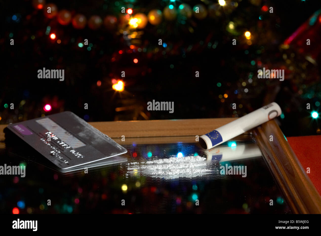 Lignes de cocaïne sur miroir simulé avec enroulé à 50 euros en espèces remarque avec carte de crédit platinum in front of Christmas Tree Banque D'Images