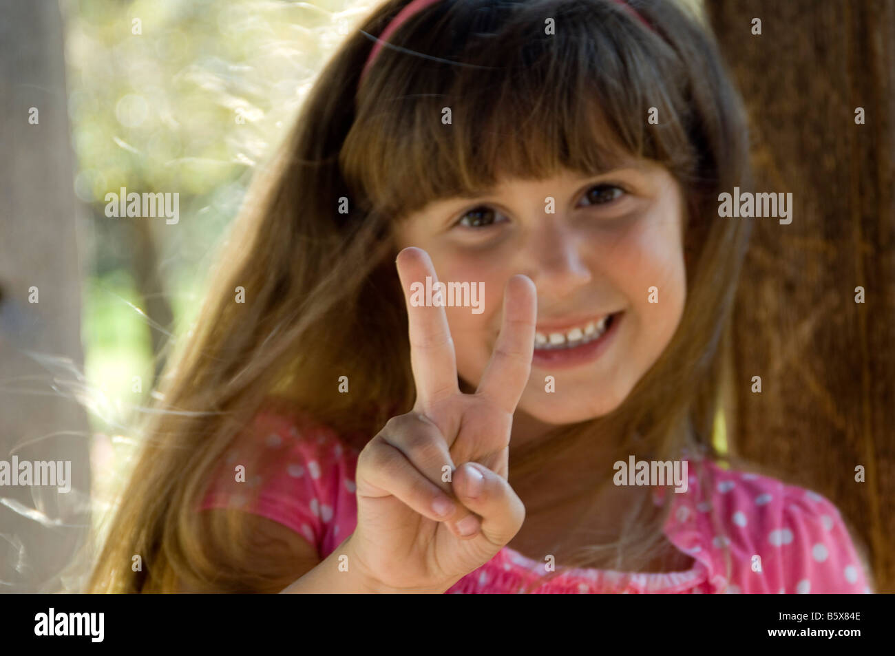 La paix : Smiling little girl making peace sign à huis clos. Banque D'Images