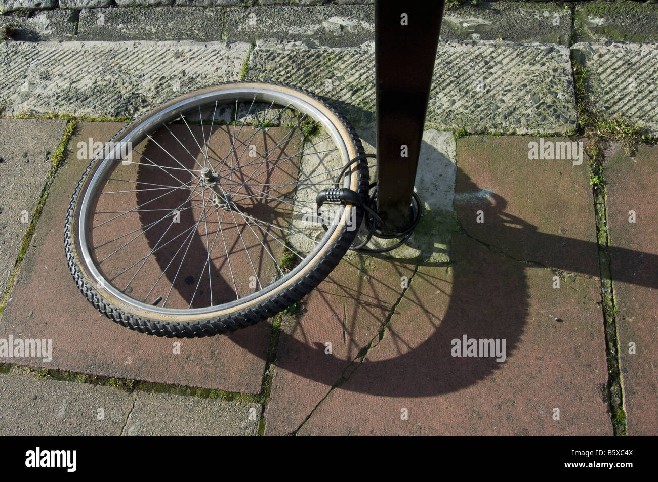 Une roue de vélo attaché à un poteau. Le reste de la moto a été volée. Banque D'Images