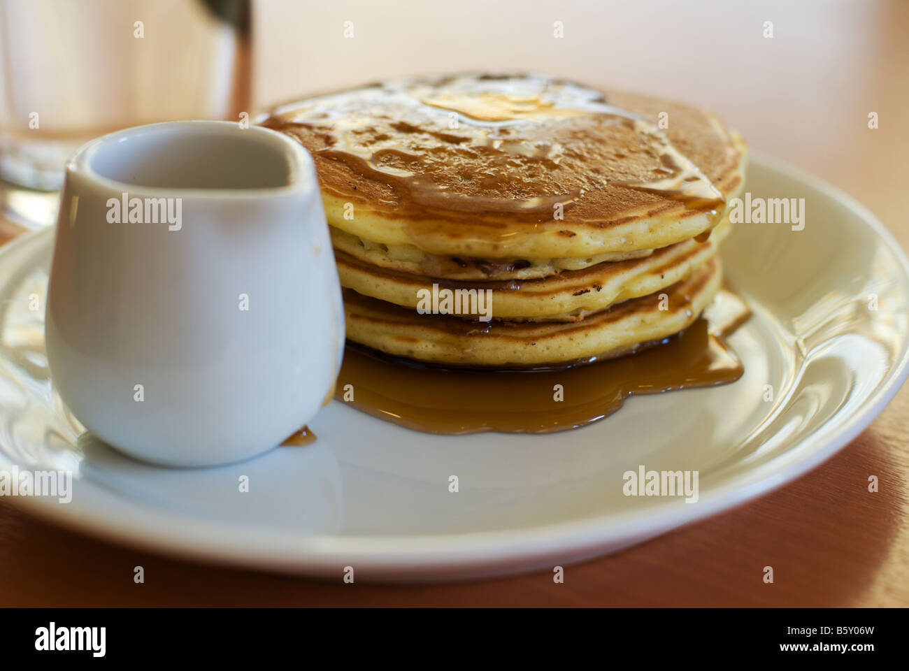 Une pile de trois Crêpes avec sirop d'érable et un pot sur une plaque blanche à un Japonais le restaurant Denny's. Banque D'Images