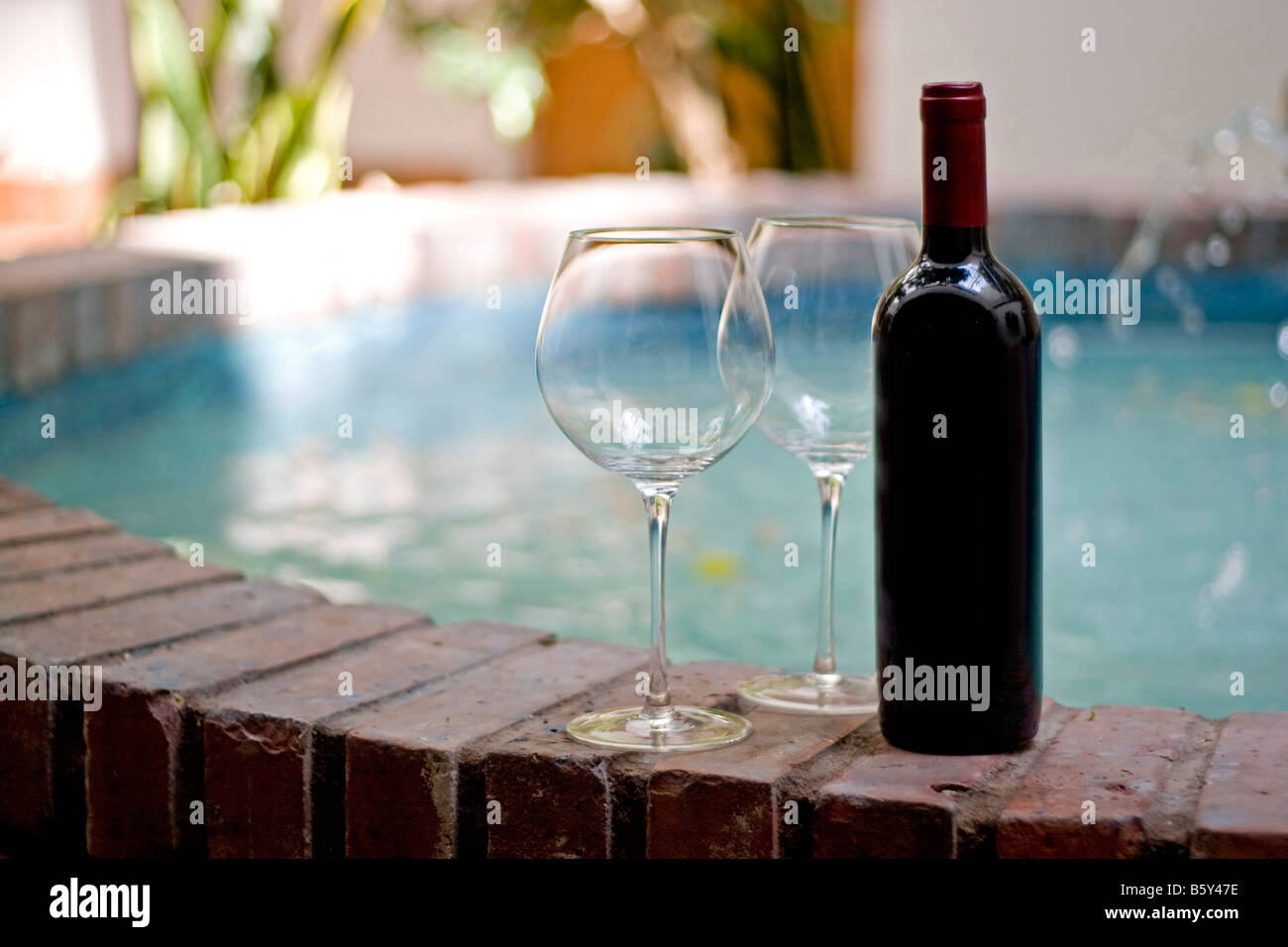 Une bouteille de vin rouge et deux verres vides de la piscine Banque D'Images