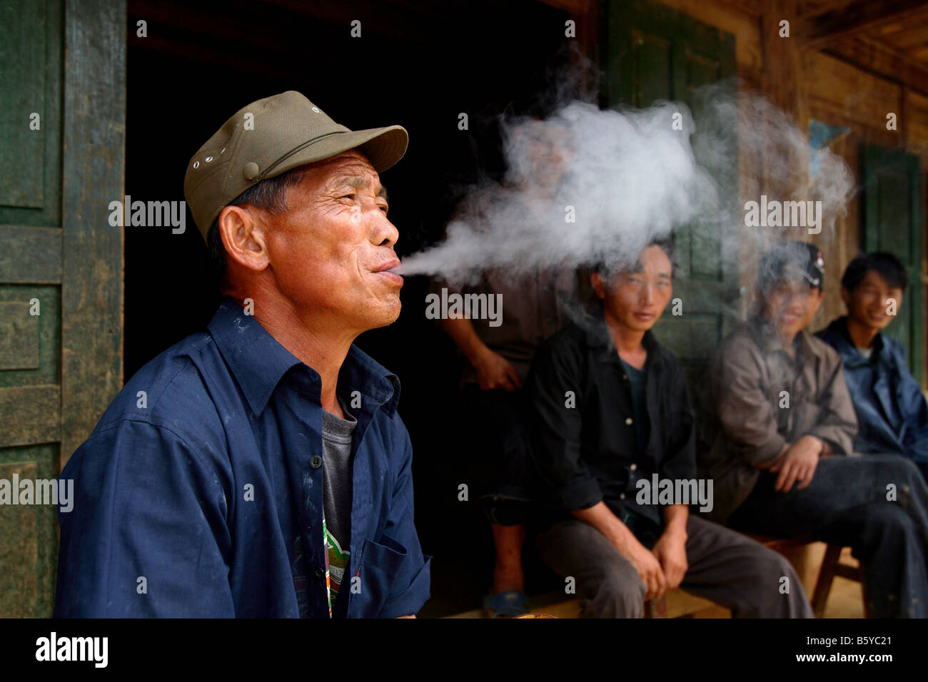 Les hommes vietnamiens pipe en face de vieille maison Bac Ha dans le nord du Viet Nam Banque D'Images