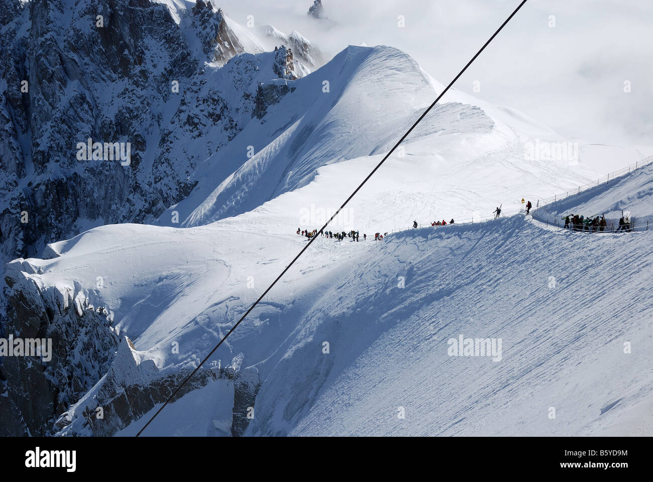 Pente de neige avec les skieurs de montagne et glacier contre des hauts sommets des Alpes Mont Blanc France câble en acier à l'avant-plan Banque D'Images