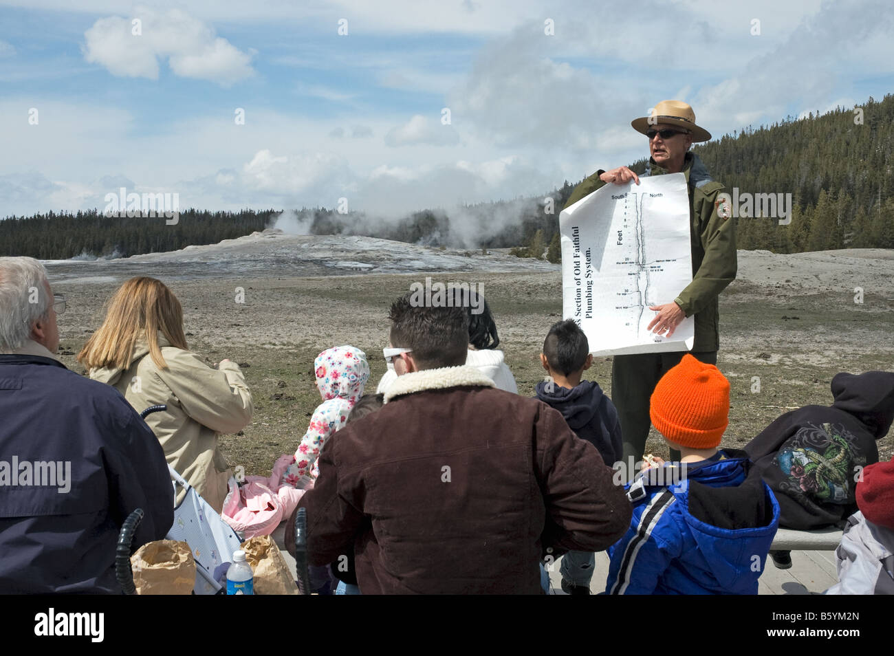 Avec le célèbre geyser Old Faithful derrière lui, un garde forestier du Parc National de Yellowstone explique sa plomberie pour visiteurs Banque D'Images
