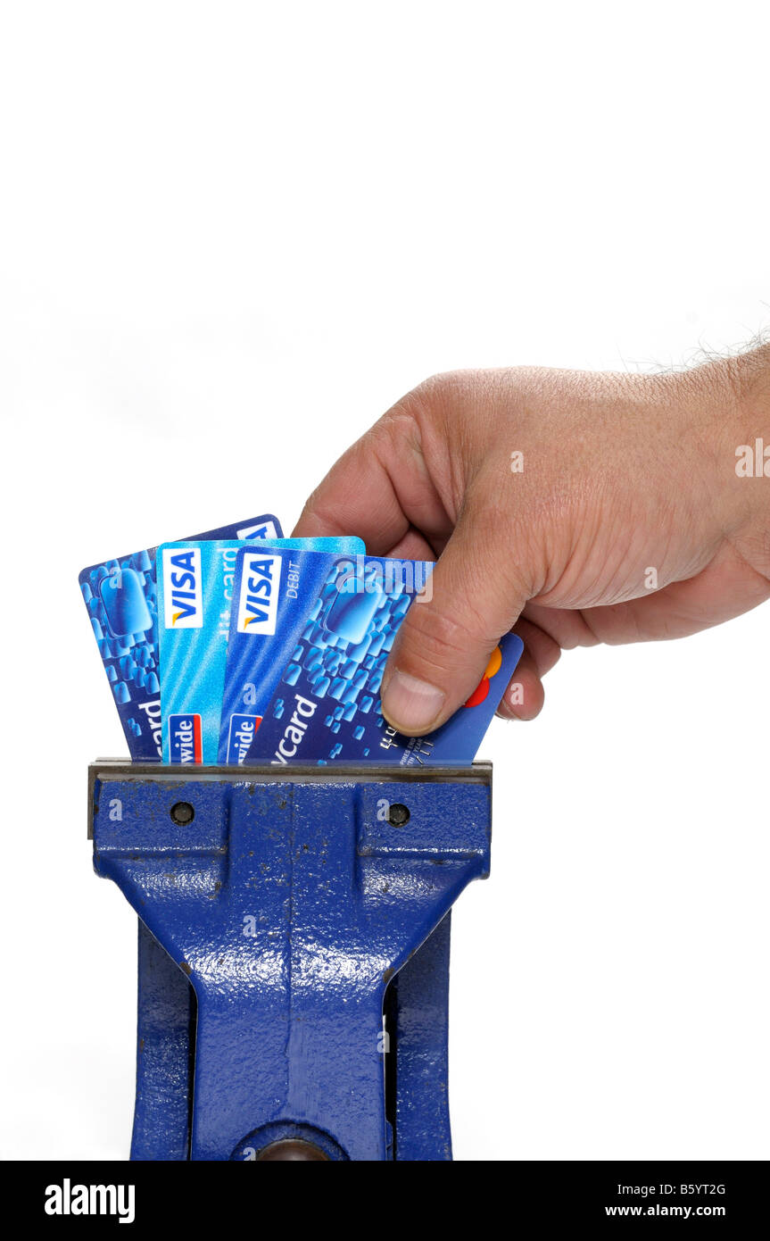 Cartes de crédit serré dans un étau avec une main essayant de supprimer ou de les placer dans l'étau Banque D'Images
