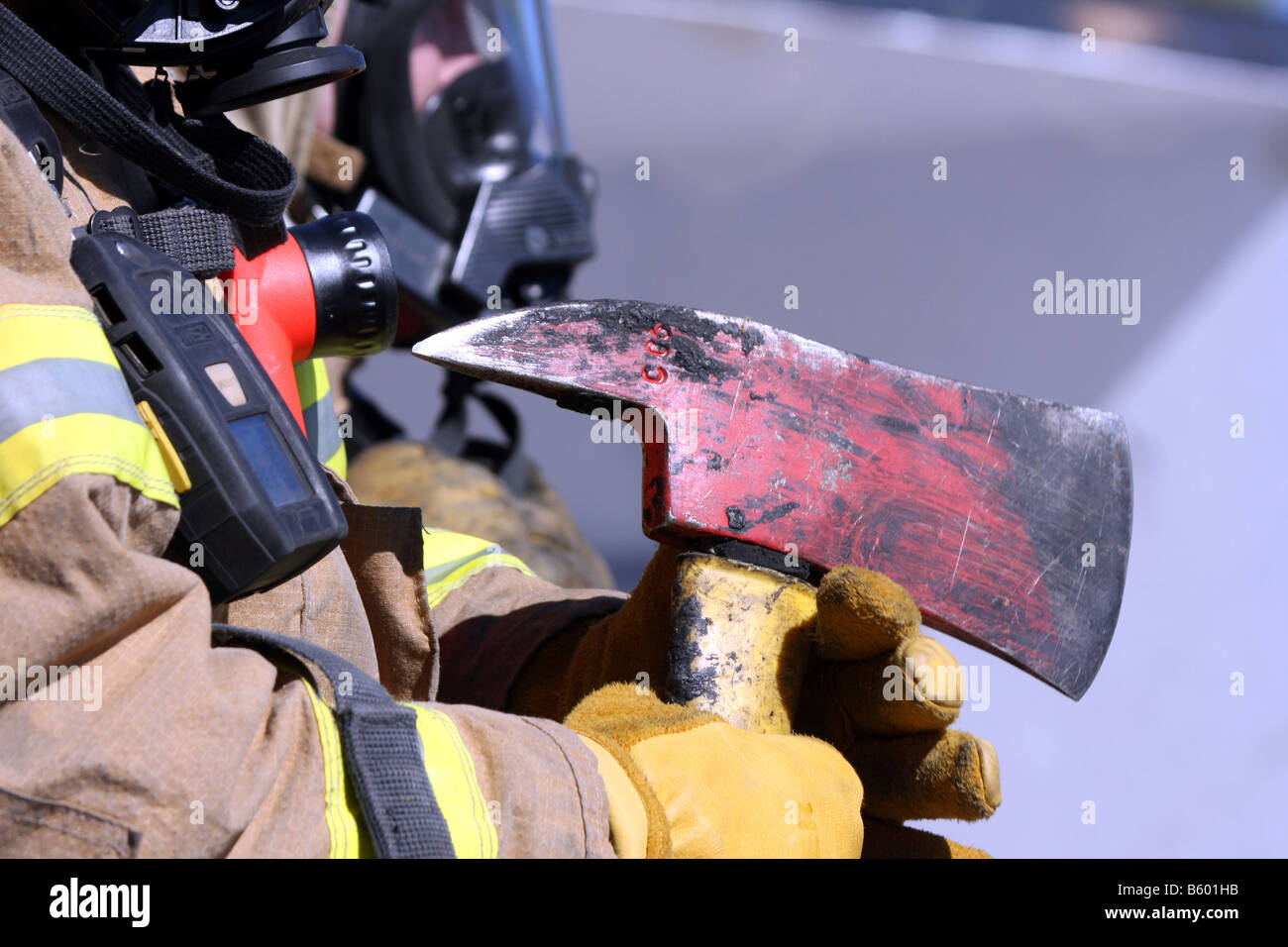 Un pompier tenant sa hache qui avaient brûlé des débris sur elle d'un incendie Banque D'Images