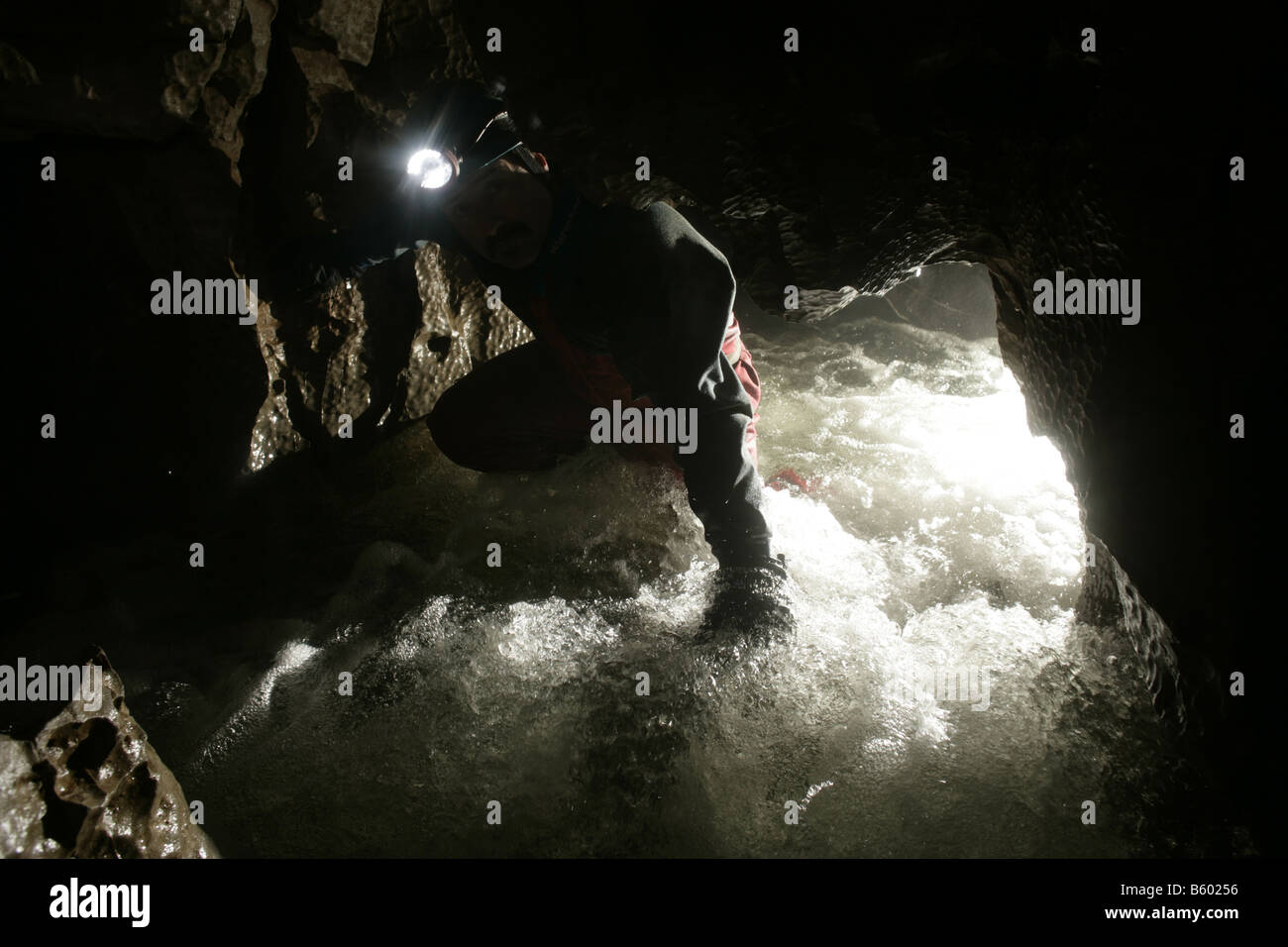Le spéléologue explore un flux passage dans la grotte du pont dans la vallée de Neath du sud du Pays de Galles dans le parc national de Brecon Beacons Banque D'Images