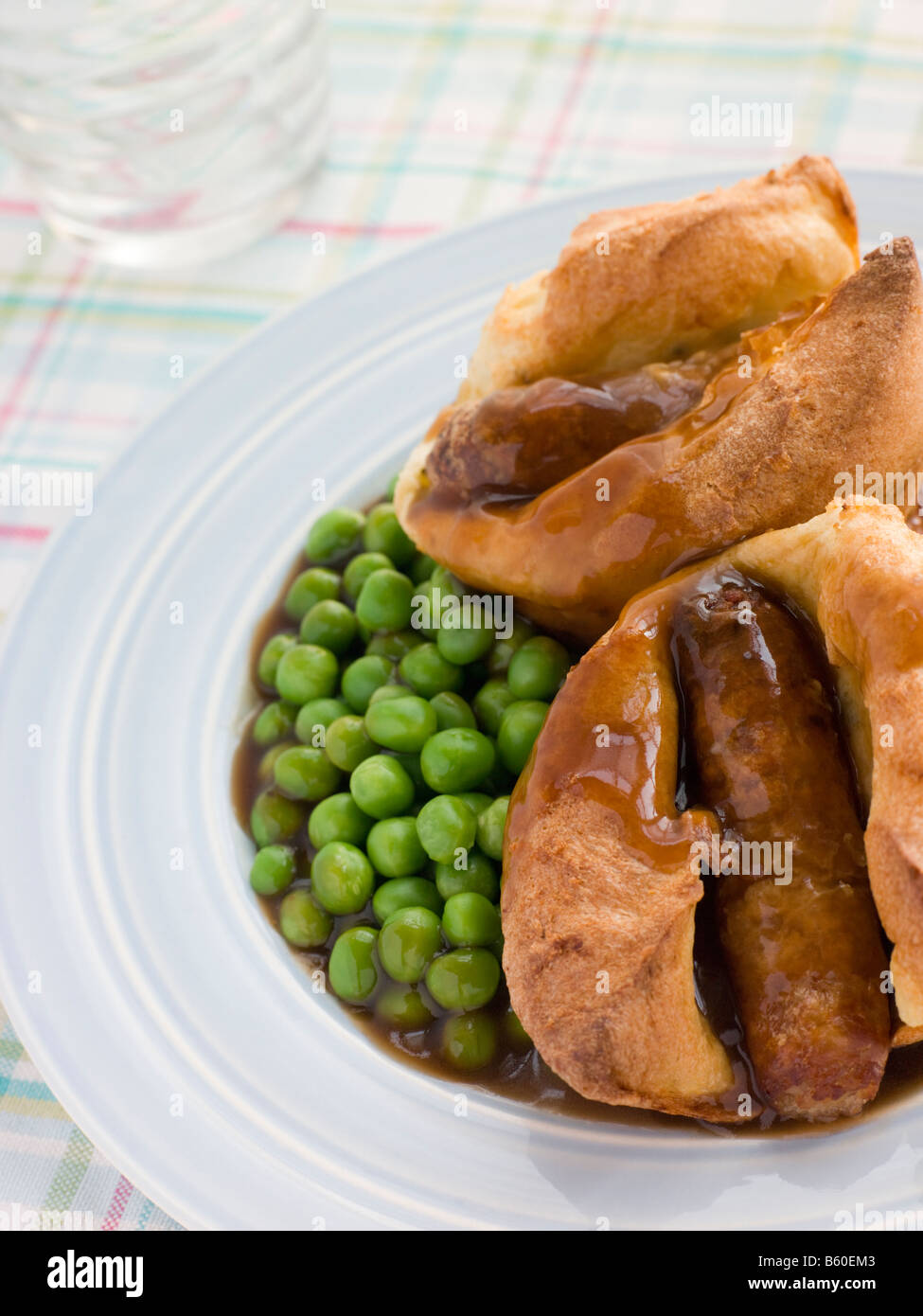 Crapaud individuels dans les trous avec la sauce et les petits pois Banque D'Images