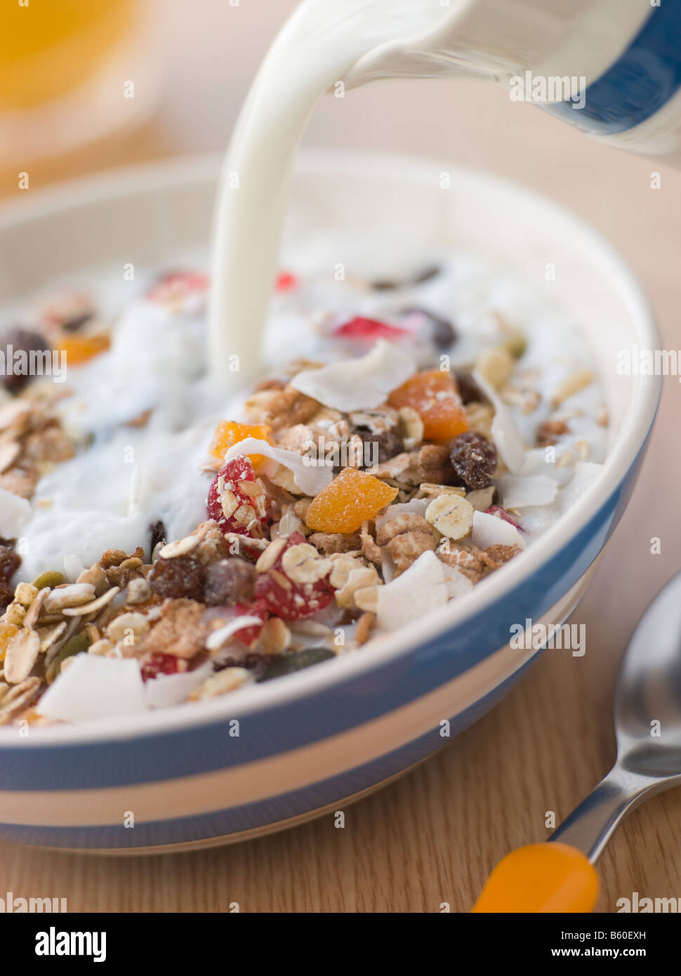 Verser le lait au-dessus d'un bol de Museli Banque D'Images