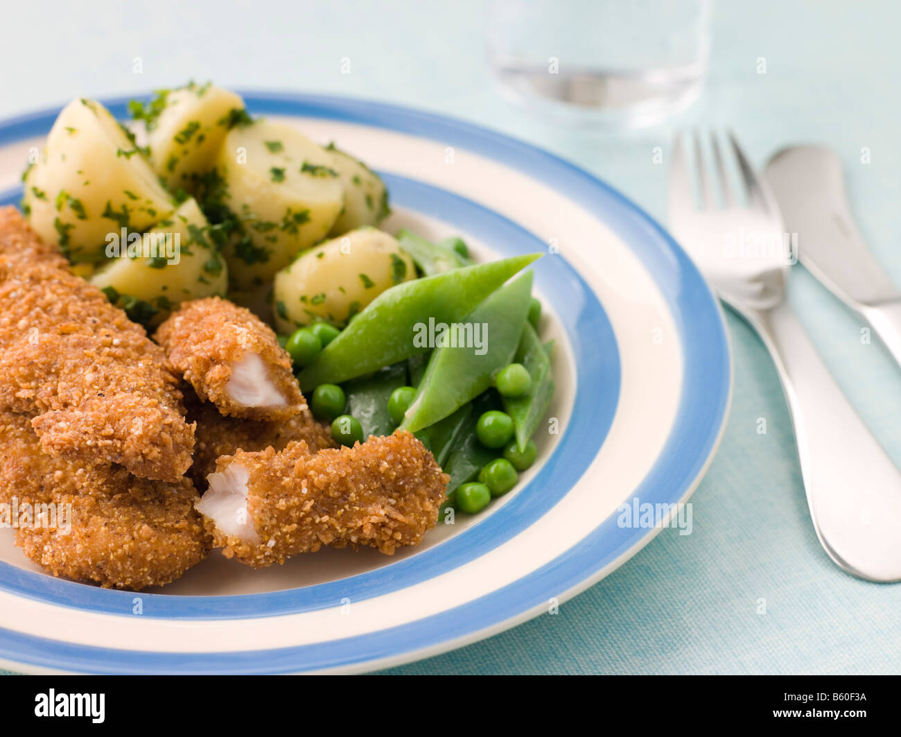 Goujons de poulet avec pommes de terre nouvelles au beurre d'herbes et de légumes verts. Banque D'Images