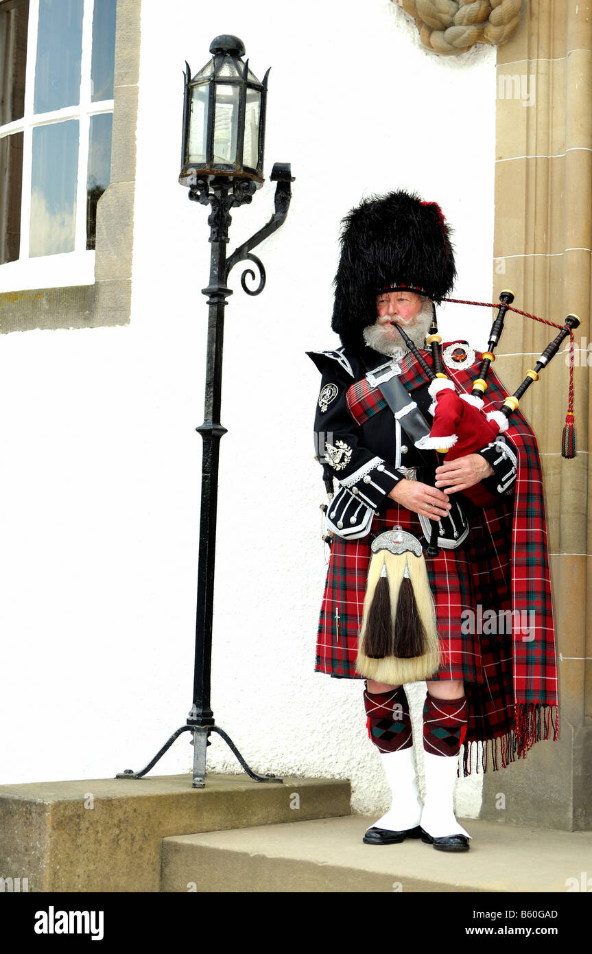 Cornemuse portant un costume traditionnel écossais avec un chapeau à la  peau d'ours et kilt lors d'une entrée du château, l'Écosse, Grande-Bretagne  Photo Stock - Alamy