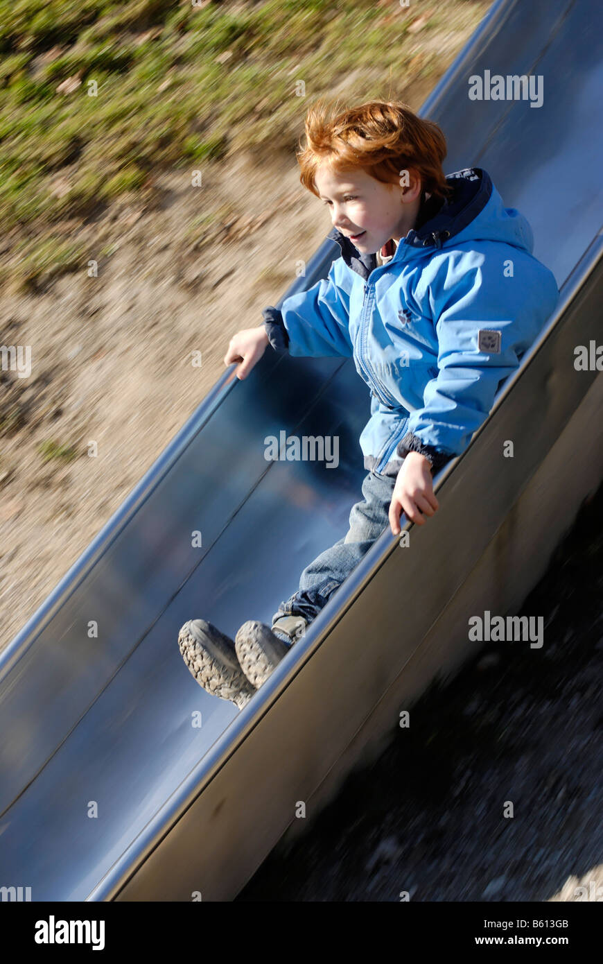 Enfant sur une diapositive sur une aire de jeux Banque D'Images