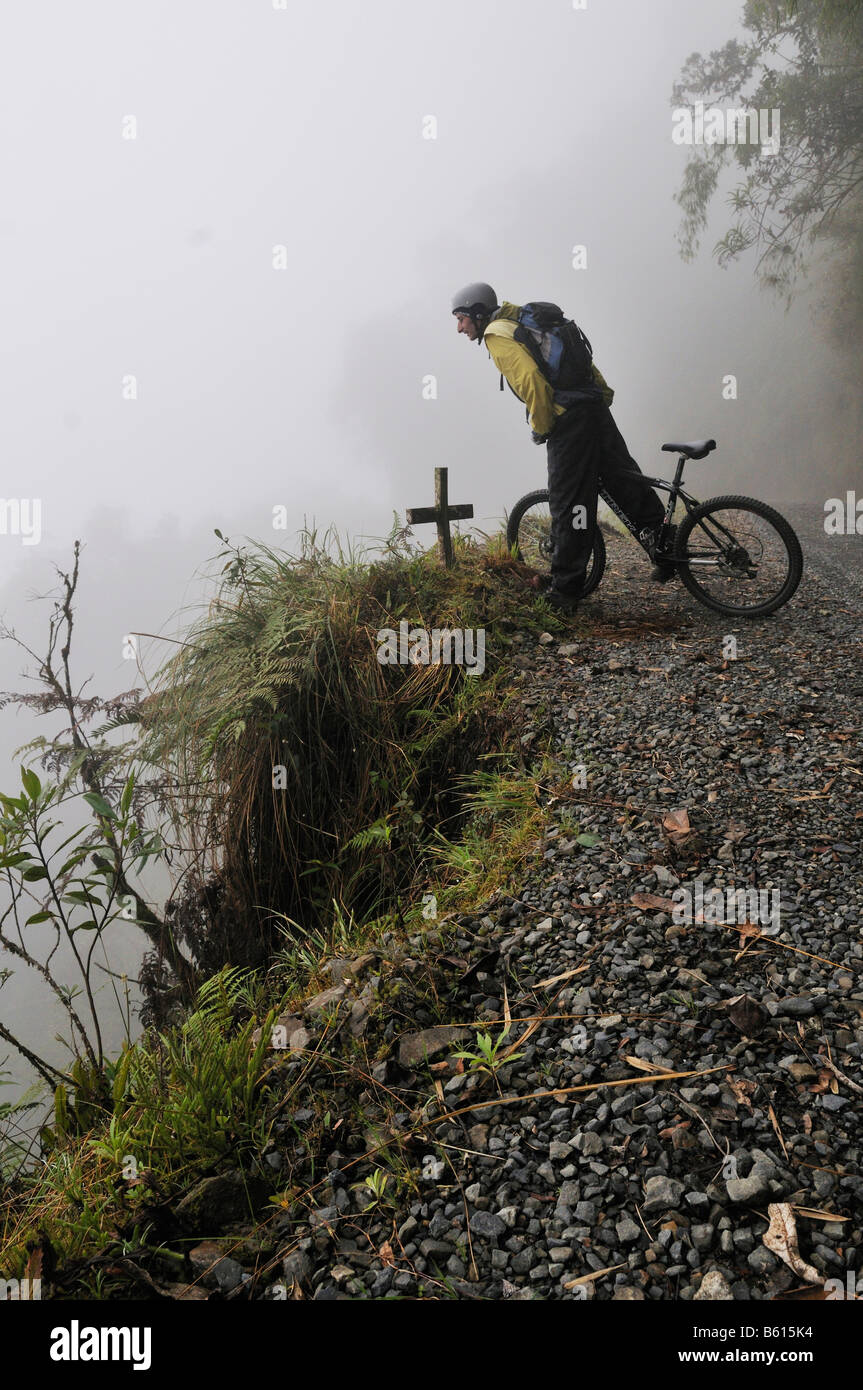 Croix du Souvenir devant un mountainbiker sur la Deathroad à inquiet sur un remblai, Yungas, La Paz, Bolivie Banque D'Images