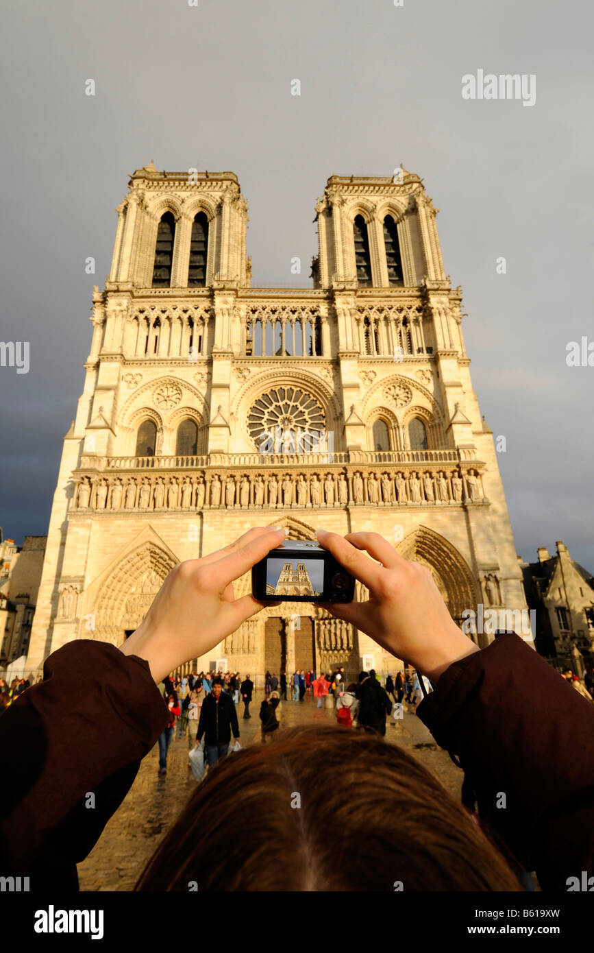 Touristiques femelle avec un appareil photo numérique de prendre une photo de Notre Dame de Paris avec portail principal, vue ouest, Paris, France, Europe Banque D'Images