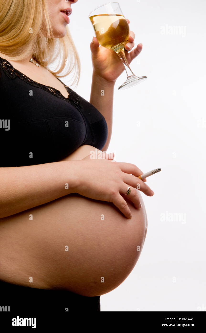 A 8 mois et demi de femme enceinte fume une cigarette et de boire un verre  de vin blanc en studio contre fond uni, UK Photo Stock - Alamy