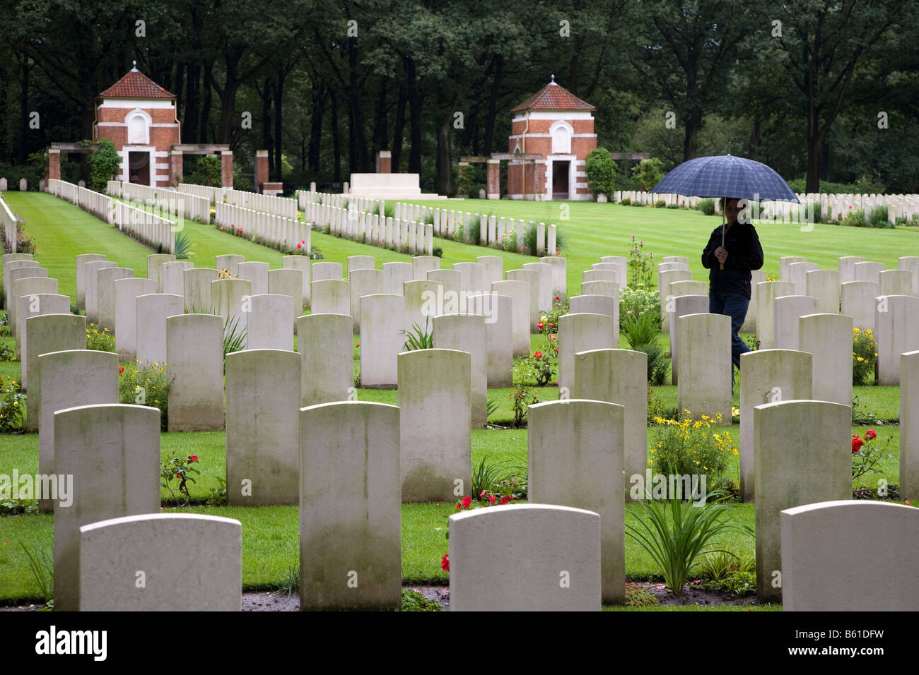 Femme marche dans la pluie dans le cimetière militaire du Commonwealth Britannique Arnhem Pays-Bas Banque D'Images