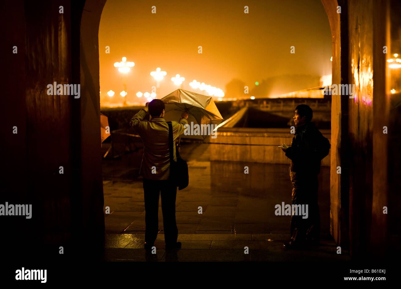 Deux hommes s'abritent de la pluie près de la place Tiananmen à Beijing en Chine en avril 2008 Banque D'Images