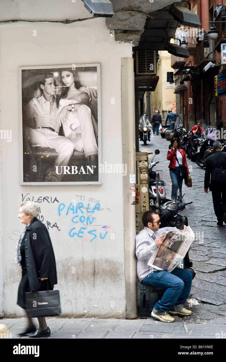 Scène de rue dans le quartier de Toledo, l'homme en lisant les journaux, vieille femme sous une affiche d'un modèle de façade, l'effritement, Naples Banque D'Images