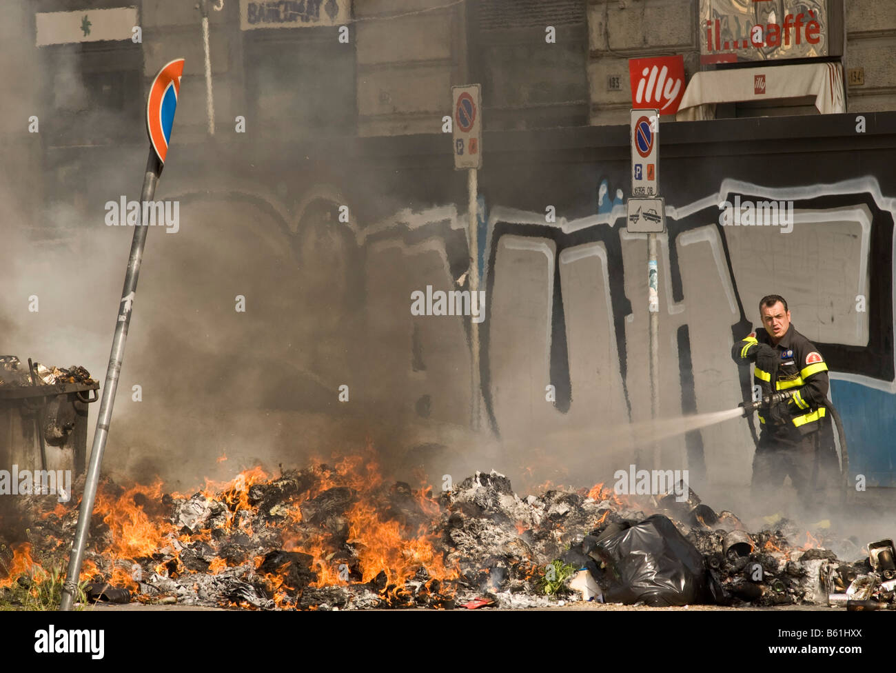 Pompier arrosant un tas de brûler les ordures ménagères qui parfois s'enflamme spontanément dans la chaleur de l'été, Naples Banque D'Images