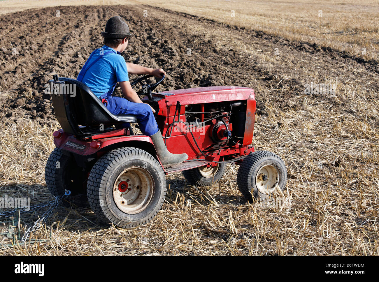 Jeune garçon conduisant un vieux tracteur de pelouse Toro à travers un champ, Erntefest Angermunder Treckerfreunde Rhine-Westp, Duesseldorf, Nord Banque D'Images