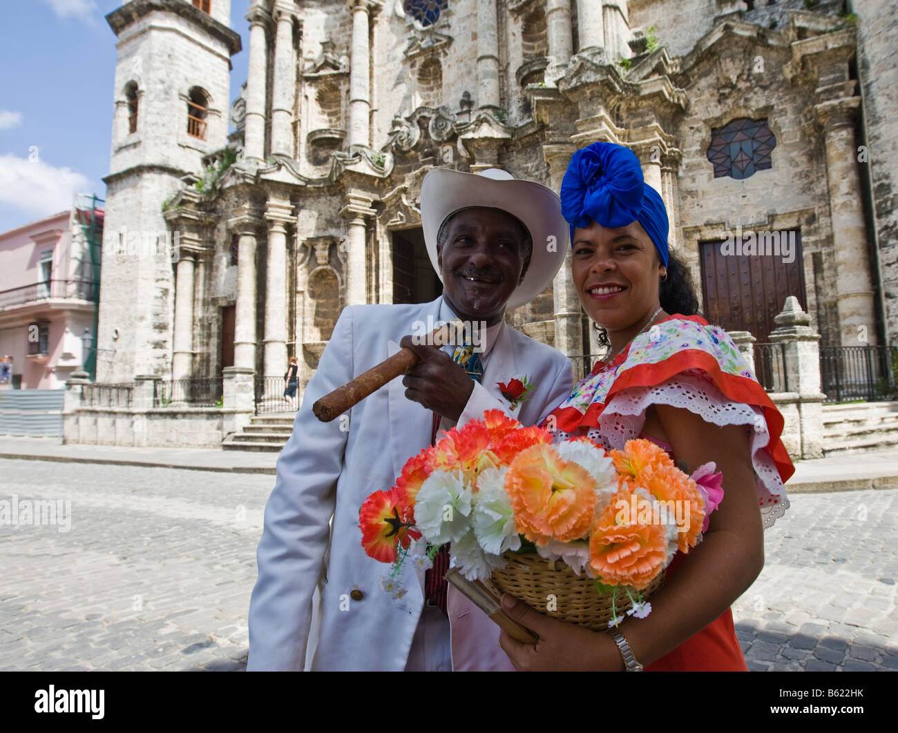 Femme tenant des fleurs et homme tenant un cigare tout en étant photographié par les touristes, le quartier historique de La Havane, Cuba, Caraïbes Banque D'Images