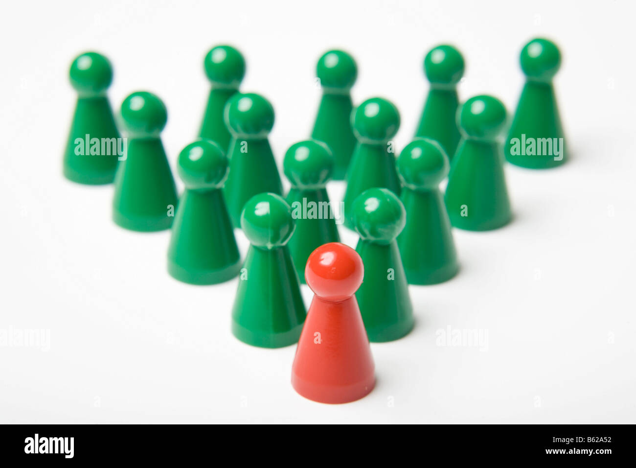Pièces de jeu Vert debout derrière une seule pièce de jeu rouge, symbolique du leadership Banque D'Images